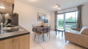 A modern kitchen with a dining area, a sofa, and a large window with a view. - Deauville II 010 with parking by Interhome (Bredene)