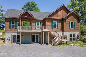 A two-story log cabin with a balcony, a front porch, and a staircase leading to the upper level. - Signature Rustic Escape w/ Pool Table & Hot Tub (McHenry)