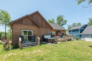 Una cabaña de madera con terraza, jacuzzi y un área de estar al aire libre techada.