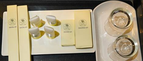 A tray with a dental kit, shaving kit, and two empty glasses on a kitchen counter.