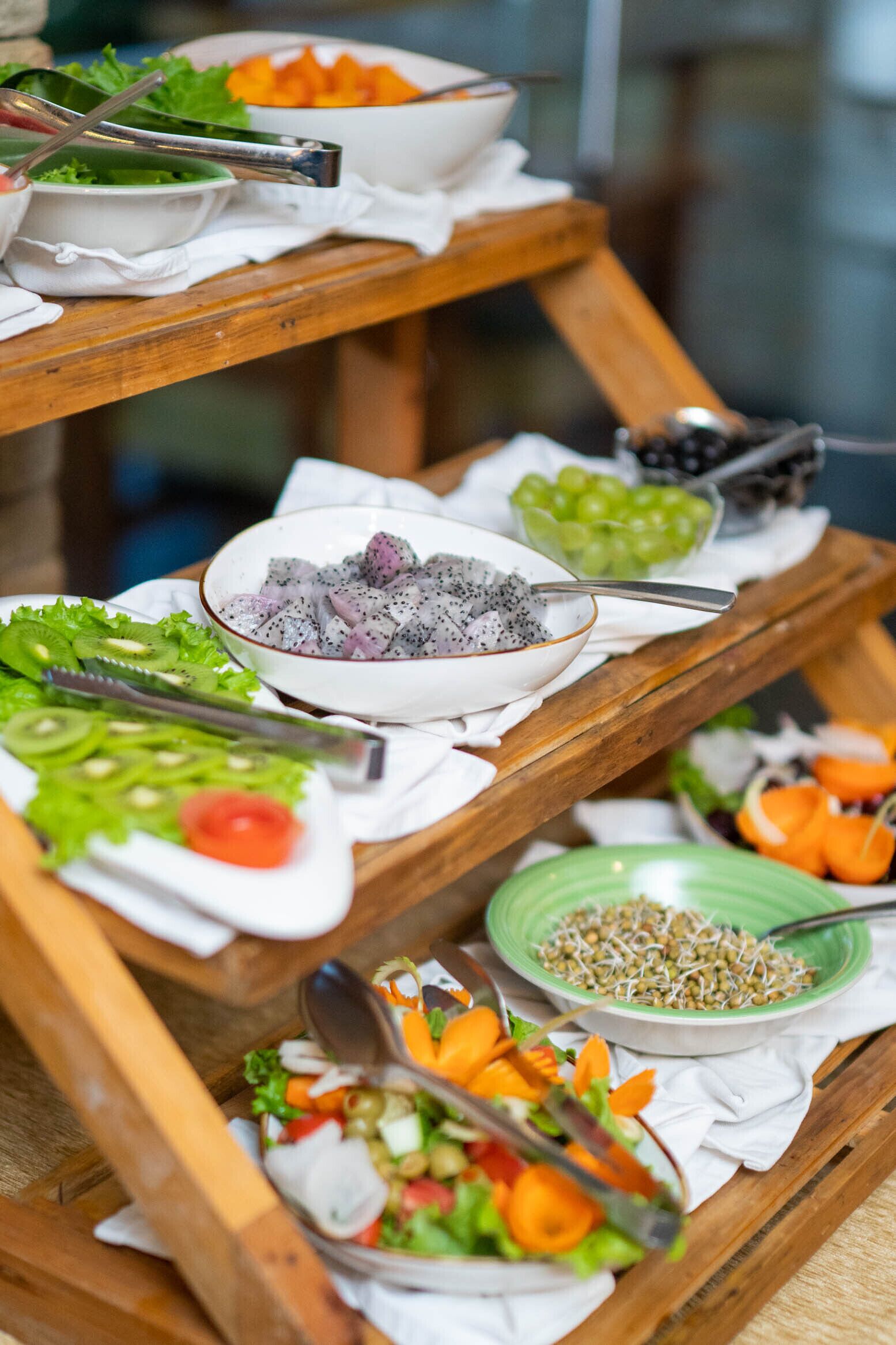 Une table de buffet proposant divers plats, notamment des salades, des fruits et des légumes.