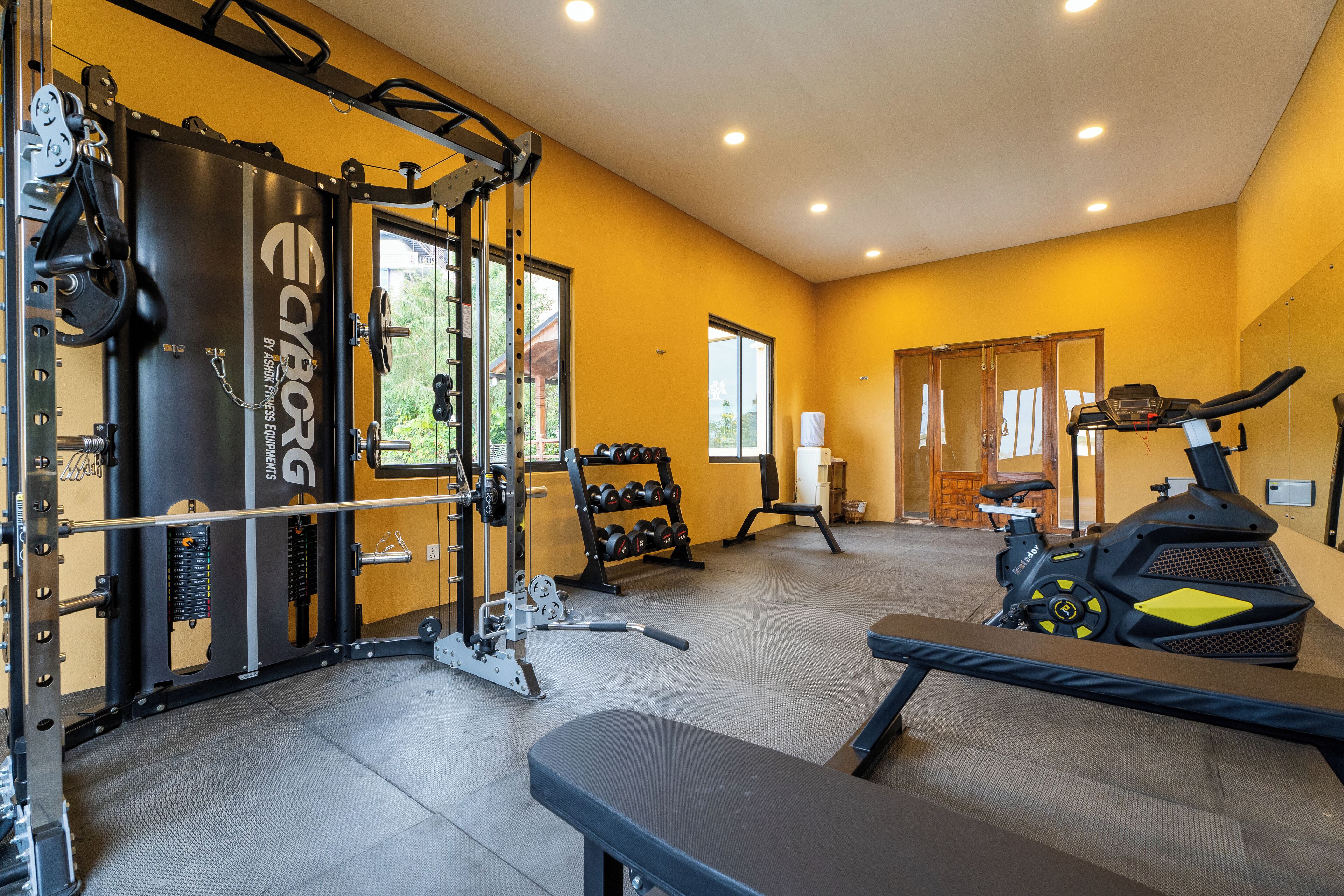 A gym with weightlifting equipment, treadmills, and dumbbells.