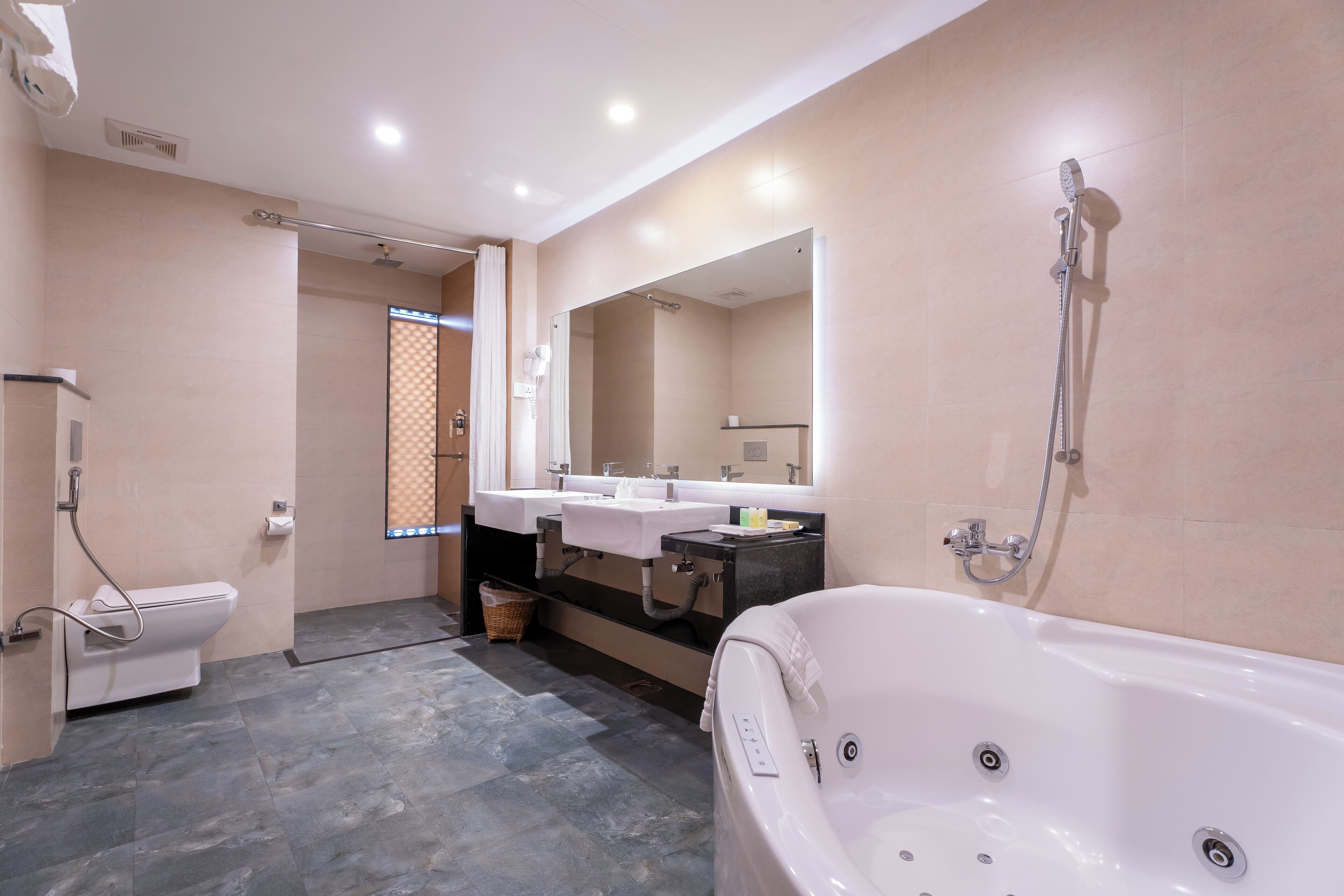 A modern bathroom with a bathtub, two sinks, a toilet, and a shower.