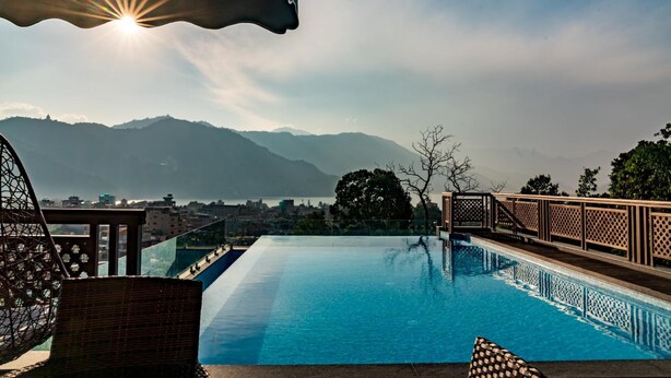 Une piscine offrant une vue sur les montagnes et sur le paysage urbain en arrière-plan.