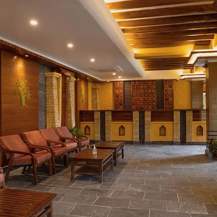 A lobby with wooden paneling, stone columns, and a seating area with chairs and tables.
