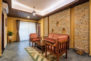 A cozy living room with a brick wall, wooden furniture, and a ceiling fan.