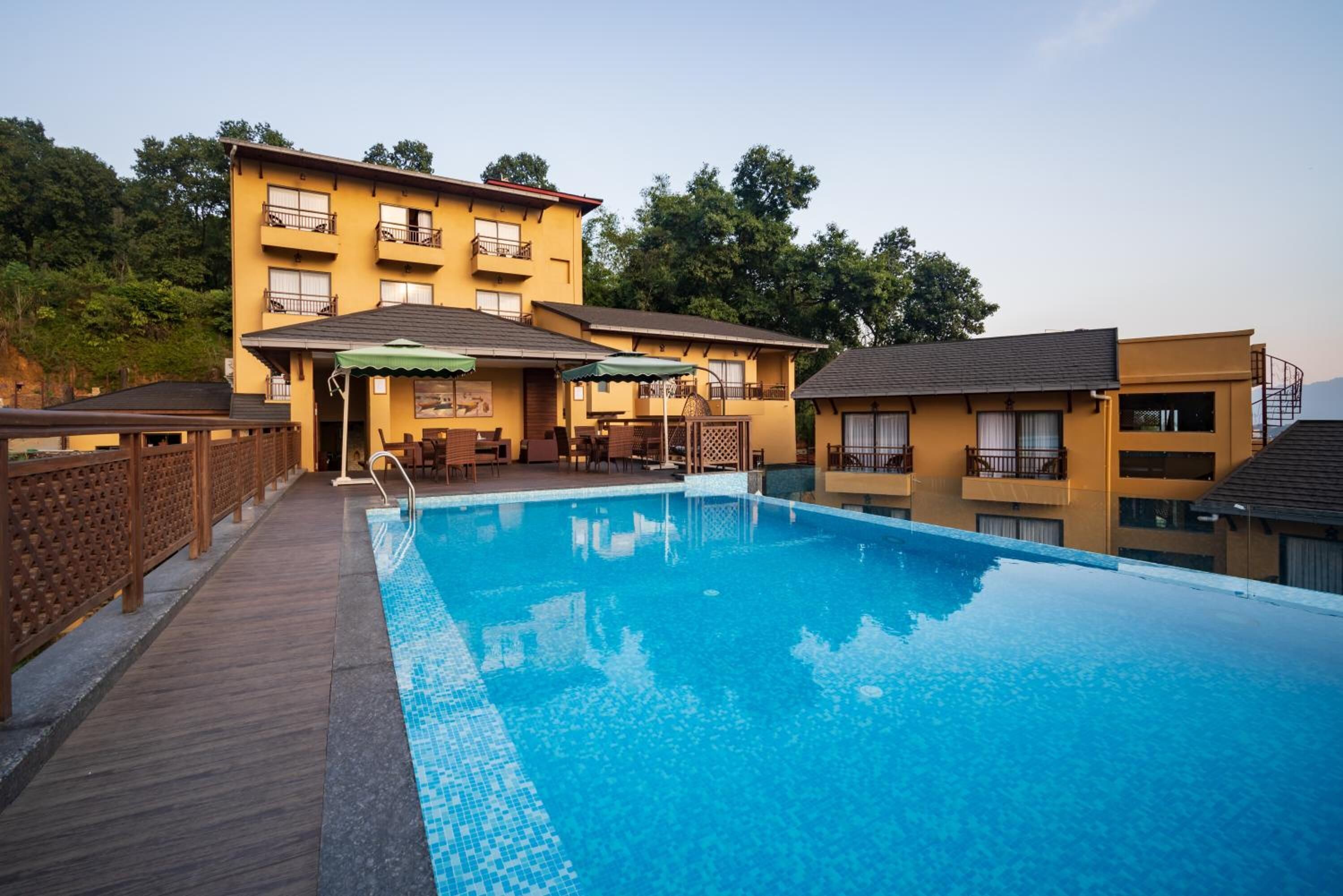 A hotel with a swimming pool, wooden deck, and outdoor seating area.