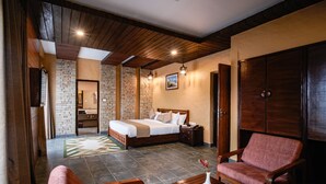 Une chambre d’hôtel avec un plafond en bois, des murs en briques, un lit, un bureau et deux chaises.