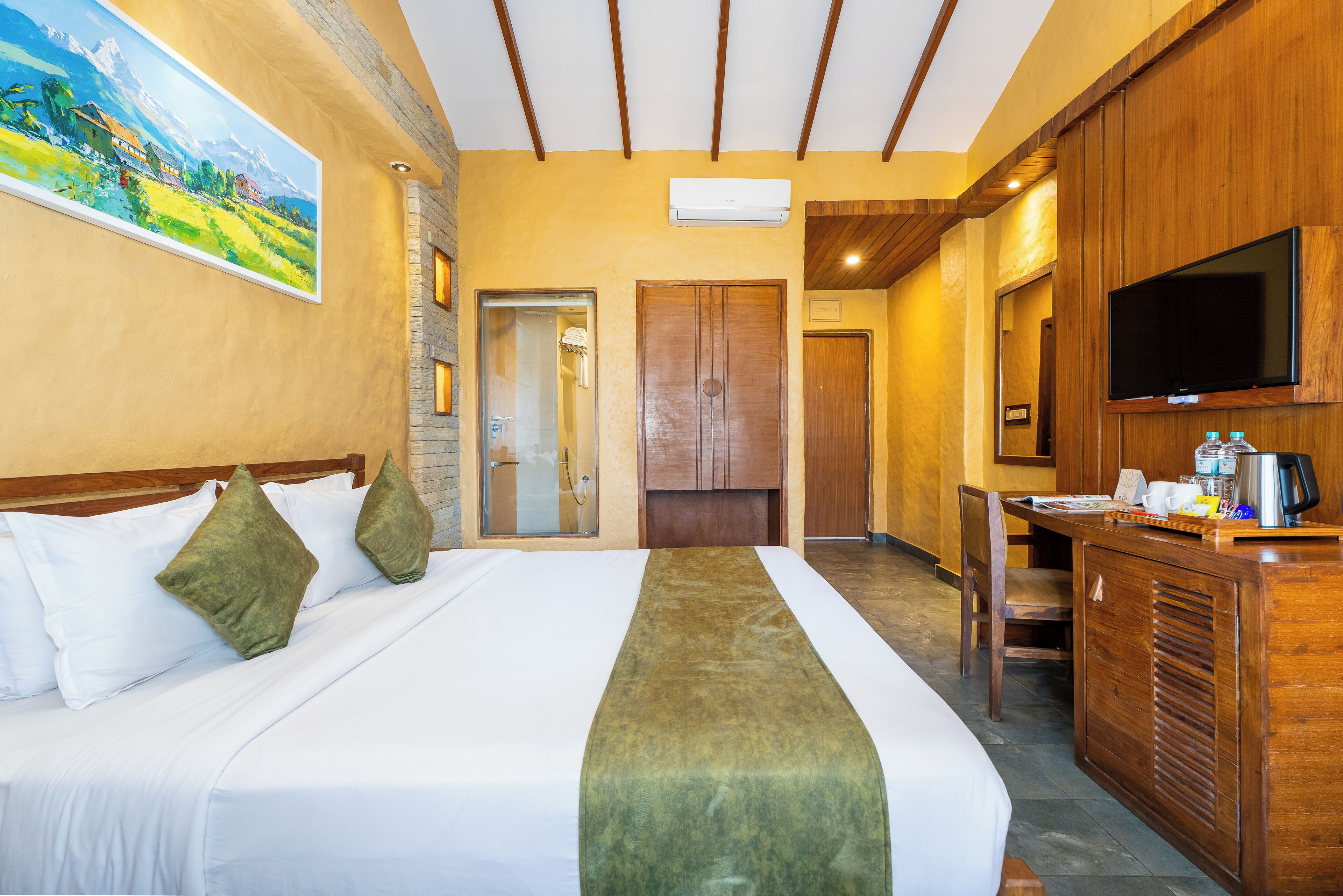 Una habitación de hotel con cama, escritorio, televisor y un cuadro en la pared.