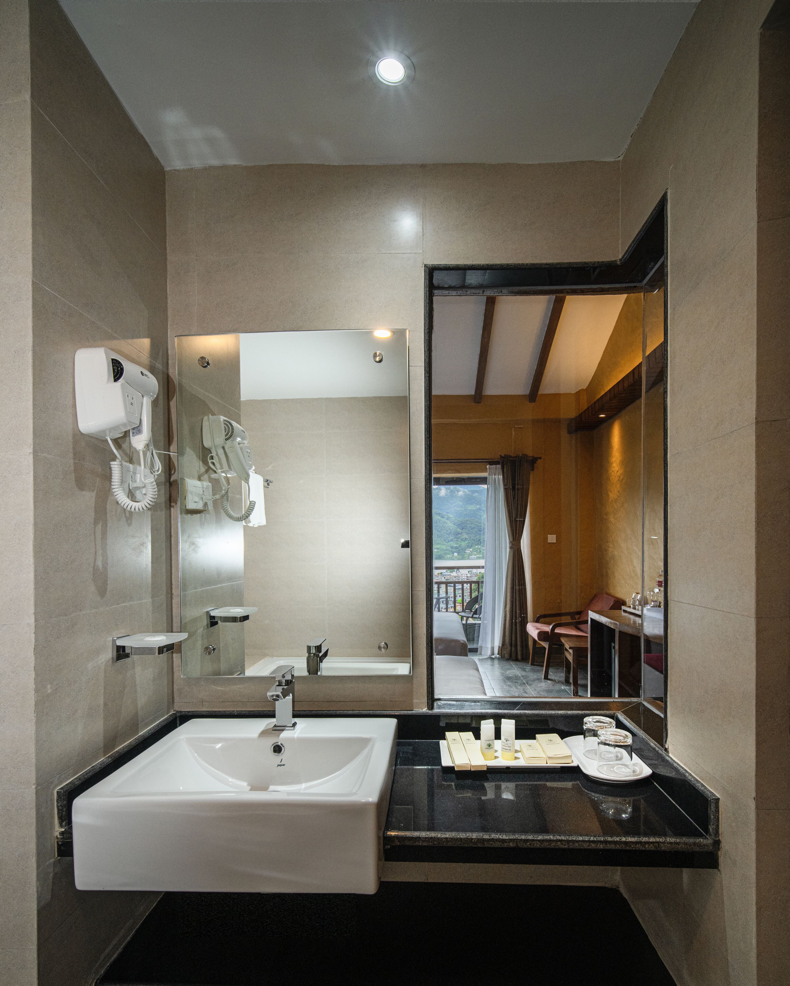 Un baño moderno con un lavamanos grande, un secador de pelo y un espejo.