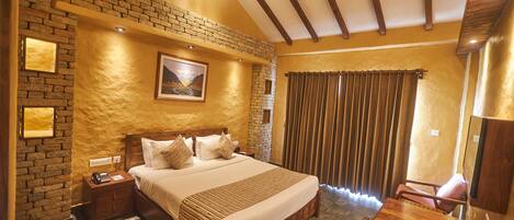 A bedroom with a brick wall, wooden bed, and a desk with a chair.