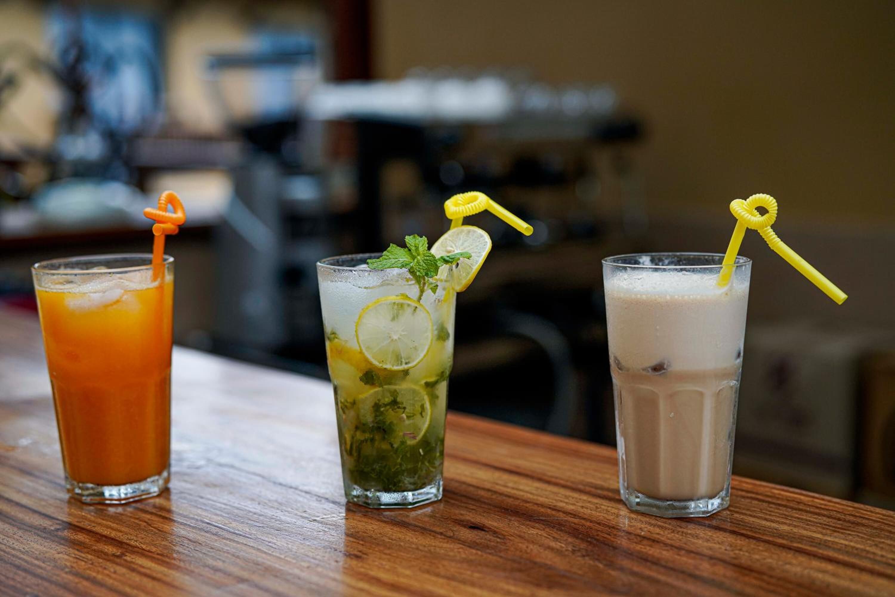 Tres vasos de bebidas sobre una mesa de madera.