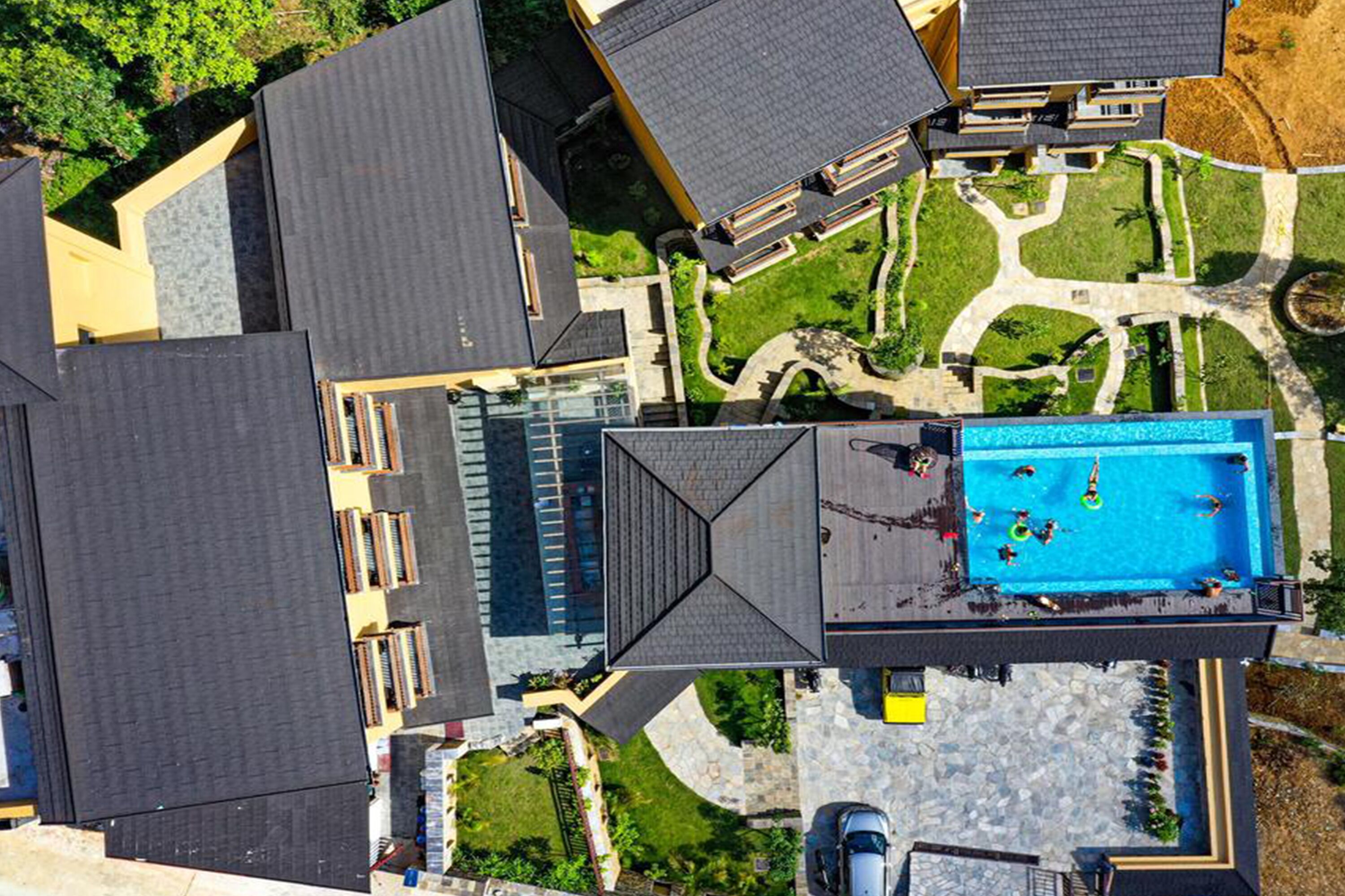An aerial view of a residential area with multiple houses, a swimming pool, and a parking area.