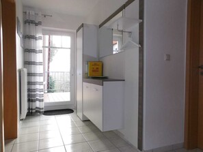A kitchen with white cabinets, a black countertop, and a window with curtains.