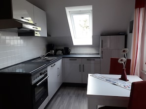 A modern kitchen with a window, a built-in oven, and a dining area with a table and chairs.