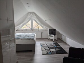 A bedroom with a bed, a TV on a stand, a window, and a ceiling fan. - Ferienwohnung 3 - Ferienwohnung Haus Bikker (Ihlow)