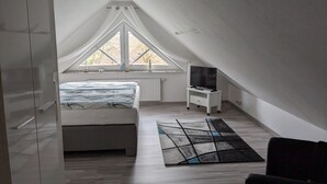 A bedroom with a bed, a TV on a stand, a window, and a ceiling fan. - Ferienwohnung 3 - Ferienwohnung Haus Bikker (Ihlow)