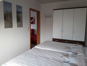A bedroom with a bed, a wardrobe, and two wall-mounted pictures.