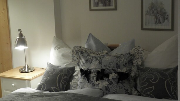 A bedroom with a bed, pillows, a nightstand with a lamp, and two framed pictures on the wall. - Sleep well apartment, Germany (Görlitz)