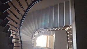 Una escalera de caracol con ventanal central, barandillas de madera y diseño moderno.