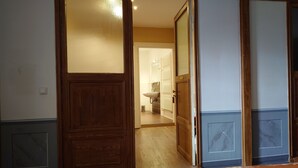 Puerta de madera con paneles de vidrio que da a un baño con lavamanos e inodoro.