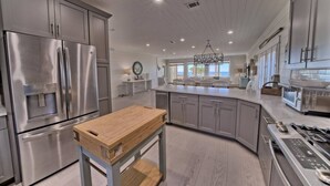 A modern kitchen with stainless steel appliances, a wooden island, and a view to the outside.