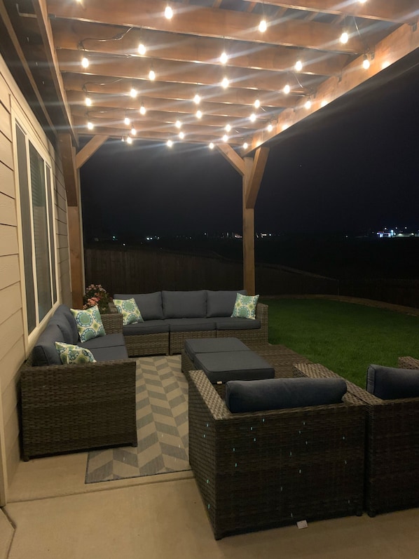 An outdoor patio with wicker furniture and a pergola with string lights. - Beautiful Spacious Contemporary Craftsman Style Home (Colorado Springs)