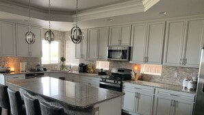 Une cuisine moderne dotée d’un grand îlot central, de meubles blancs et d’appareils électroménagers en acier inoxydable.