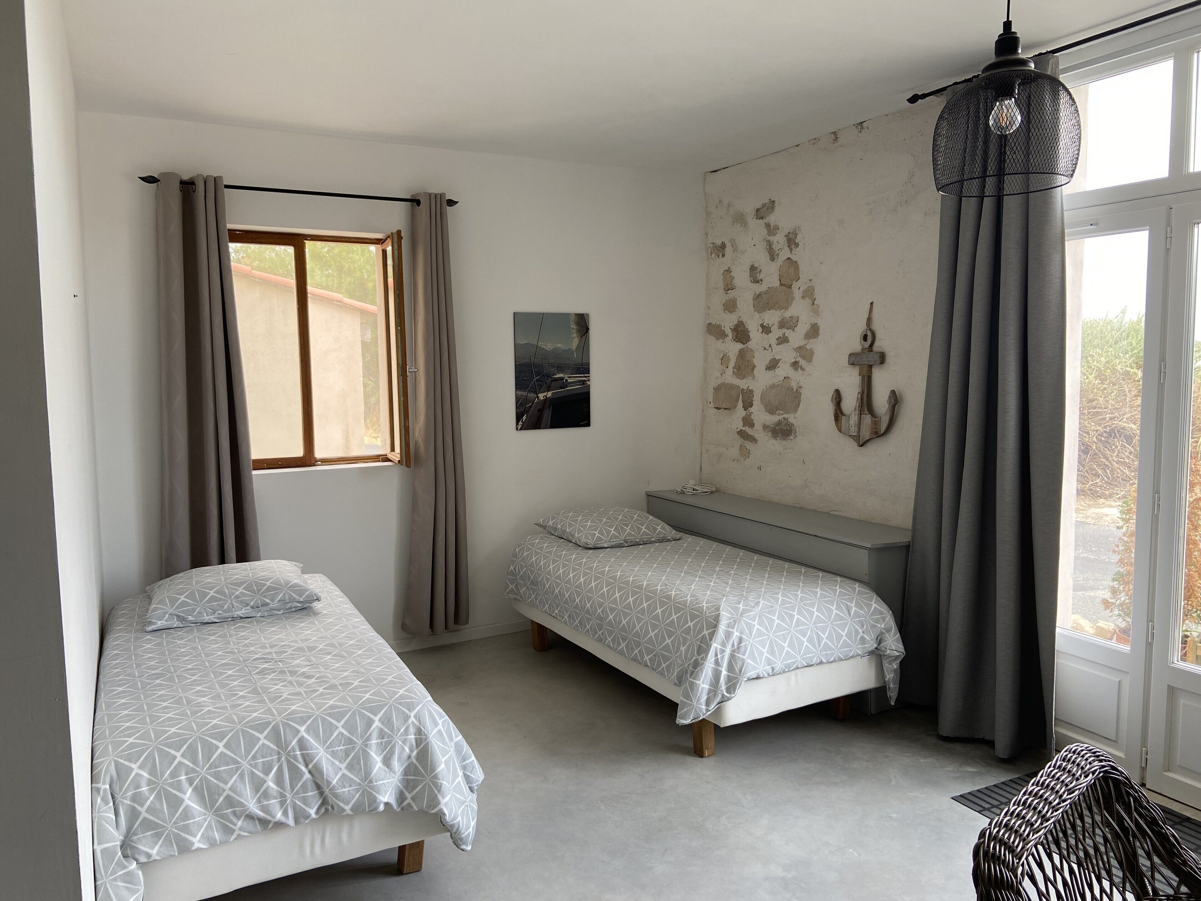 Un dormitorio con dos camas, una ventana con cortinas, una lámpara en la pared y vistas al exterior.