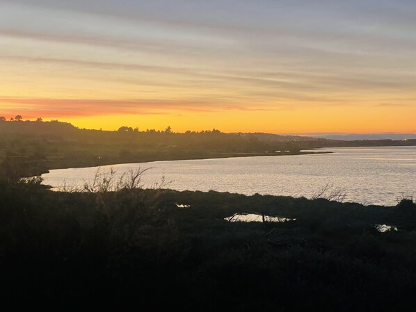 A river at sunset with a distant shoreline. - A Break by the Pond (Bages)