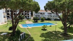 A pool area with a rectangular pool, surrounded by well-maintained grass and trees. - Pinhal Do Golf: Superb 2-bedroom apartment, renovated in 2020 near Marina (Quarteira)
