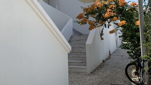 A white building with a staircase leading to a balcony, a cactus plant, and a street lamp. - Pinhal Do Golf: Superb 2-bedroom apartment, renovated in 2020 near Marina (Quarteira)