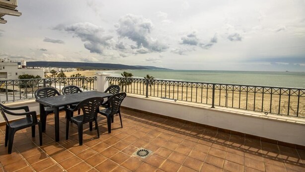Une terrasse avec une table et des chaises donnant sur une plage.