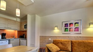 Un espacio habitable compacto con kitchenette, zona de comedor y sofá.