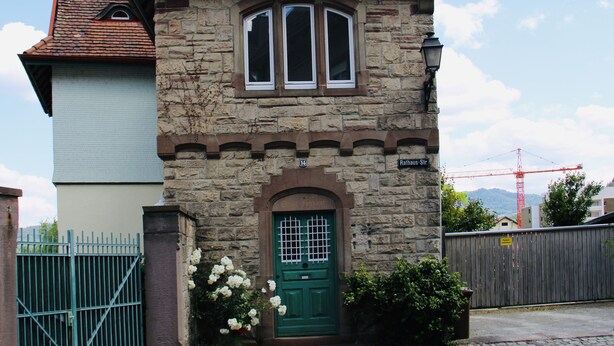 Un bâtiment en pierre avec une porte verte, une petite fenêtre et un balcon.