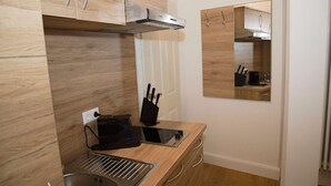 Eine moderne Küche mit Holzschränken, einem Einbauherd und einer Mikrowelle.
