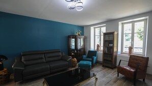 Una sala de estar con un sofá negro, un sillón verde azulado, un sillón de cuero marrón, una mesita de centro negra y una estantería.