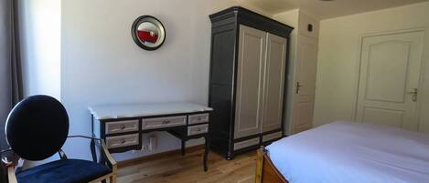 A bedroom with a bed, a desk, a chair, a wardrobe, and a mirror.