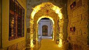 A stone corridor with an arched entrance, potted plants, and a tiled floor. - Cappadocia Cave Lodge (Nevsehir)