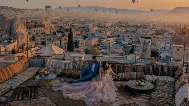 A couple on a rooftop terrace with a city view, featuring traditional architecture and a sunset. - Cappadocia Cave Lodge (Nevsehir)