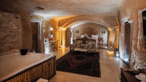 A spacious room with a large bathtub, a sofa, and a patterned rug. - Cappadocia Cave Lodge (Nevsehir)