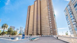 A high-rise building with a pool area in front, surrounded by other tall buildings.