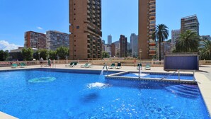 A swimming pool with lounge chairs and a view of tall buildings in the background.