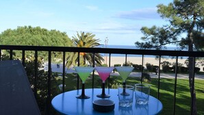 A balcony with a table set for drinks, overlooking a beach and palm trees. - Charming 2-Room Apartment Near Sea in Argelès-sur-Mer (Argelès-sur-Mer)
