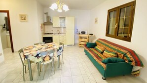 Een compacte leefruimte met een eethoek, kitchenette en een bank.