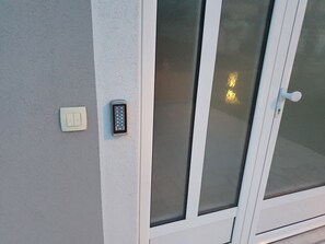 Porta com fechadura eletrônica, interruptor de luz e painéis de vidro fosco.