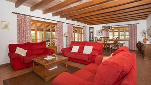 A spacious living room with red sofas, a wooden coffee table, and a dining area with a wooden table and chairs. - Finca Buena Vista, pool, air conditioning, WIFI, quiet location, beautiful view (Pollença)