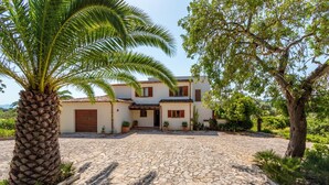 A house with a cobblestone driveway, a palm tree, and a garden with various plants. - Finca Buena Vista, pool, air conditioning, WIFI, quiet location, beautiful view (Pollença)