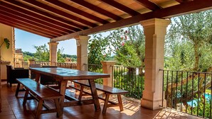 A covered patio with a wooden table and benches, surrounded by a metal railing and columns, overlooking a pool and lush greenery. - Finca Buena Vista, pool, air conditioning, WIFI, quiet location, beautiful view (Pollença)