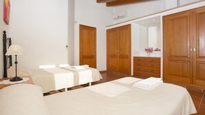 A bedroom with two beds, wooden wardrobes, a bedside table with a lamp, and a mirror. - Finca Buena Vista, pool, air conditioning, WIFI, quiet location, beautiful view (Pollença)